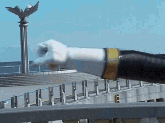 a close up of a person 's arm with a statue in the background that says ' eagle ' on it