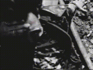 a black and white photo of a man smoking a cigarette in a dark room .