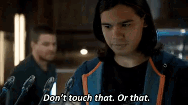 a man with long hair is standing in front of microphones and saying " don 't touch that or that " .