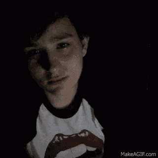 a young man wearing a rolling stones t-shirt is looking at the camera .