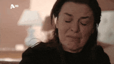 a woman is crying while sitting on a couch in a living room .