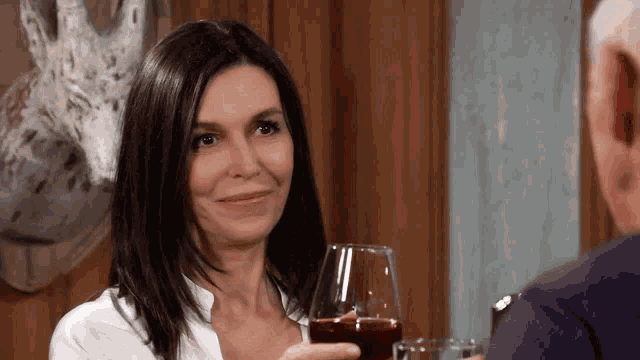 a woman holds a glass of red wine in front of a man