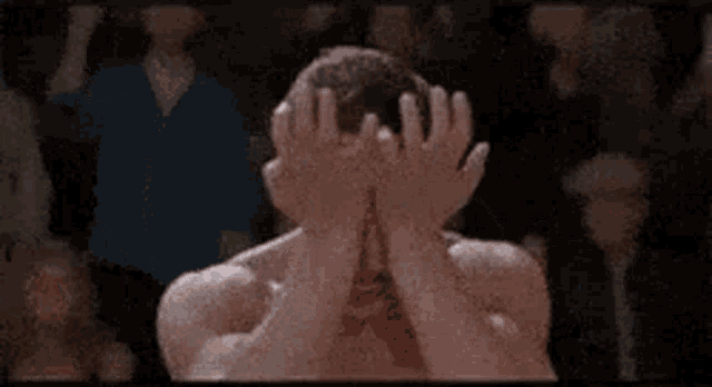 a shirtless man with a mustache is standing in front of a crowd .