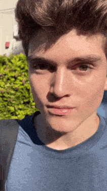 a close up of a young man 's face with a blue shirt on
