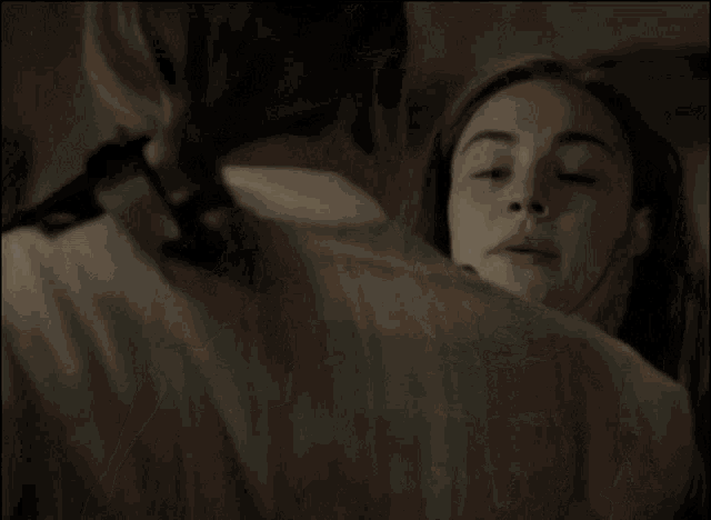 a man is touching a woman 's face with his hand in a dark room