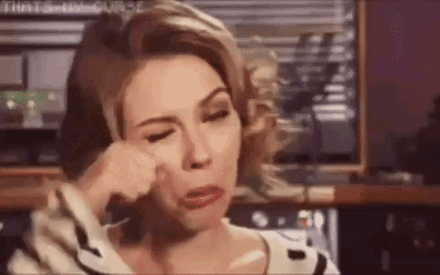 a woman is crying while sitting in front of a television .