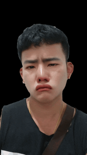 a young man with a black shirt and a brown necklace making a sad face