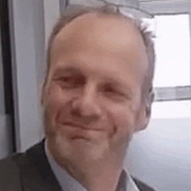 a man with a beard and a suit is smiling and looking at the camera .