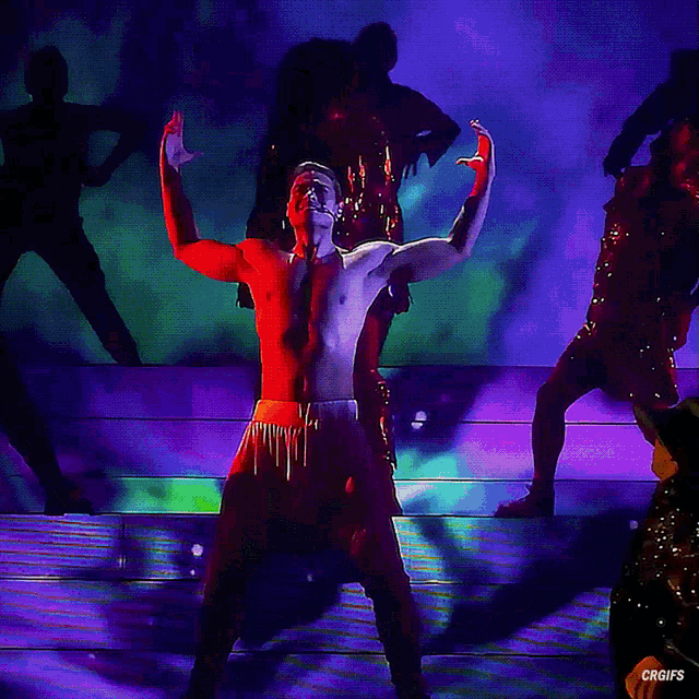 a man without a shirt is dancing on a stage with purple lights behind him and the words crgifs below him