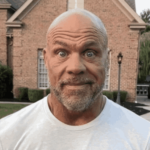 a man with a beard is making a funny face in front of a brick house