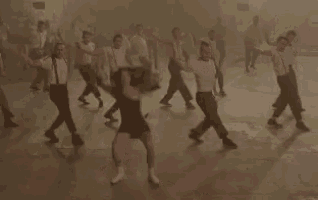 a group of people are dancing together on a dance floor in a dark room .