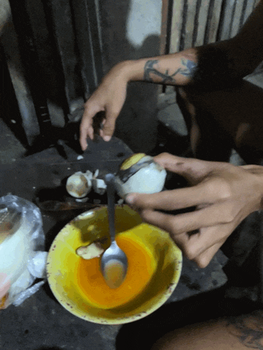 a person with a tattoo on their arm is cracking an egg into a bowl