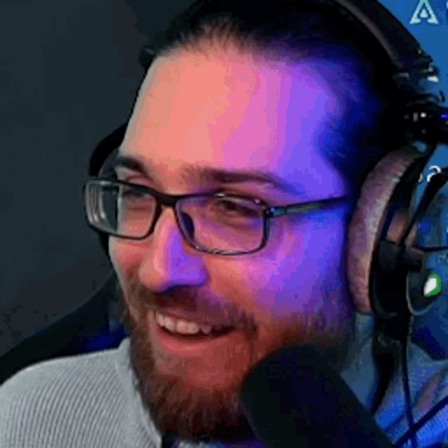 a man with a beard and glasses is wearing headphones and smiling .
