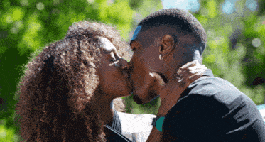 a man and a woman are kissing in front of a green background