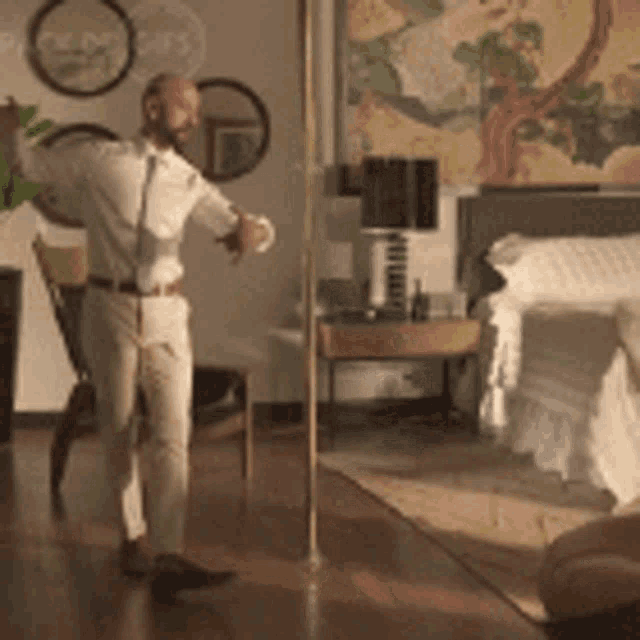 a man is dancing in a bedroom next to a bed