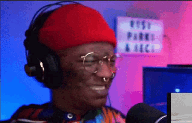 a man wearing headphones and a red beanie is smiling