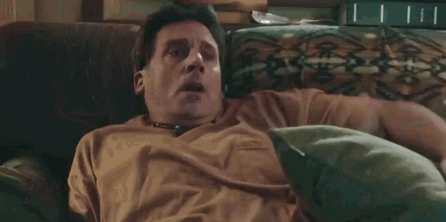 a man is sitting on a couch with his mouth wide open
