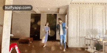 a man and a woman are running through a living room .