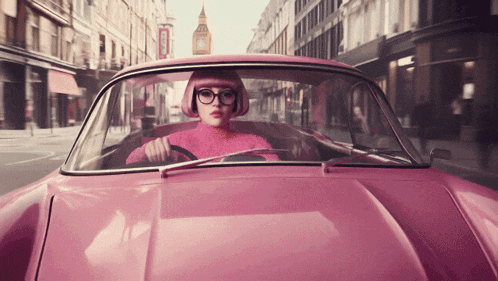 a woman driving a pink car with a big ben in the background