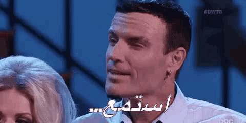 a man and a woman are sitting next to each other and the man is talking in arabic .