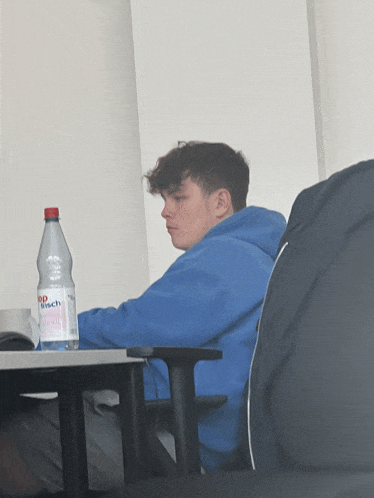 a man sits at a desk with a bottle of busch water