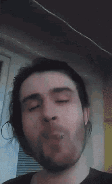 a man with a beard is making a funny face with his eyes closed