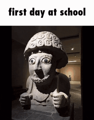 a statue of a man giving a thumbs up with the words first day at school above it