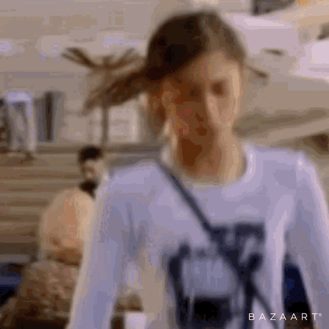 a blurry picture of a girl wearing a white shirt with the letter x on it
