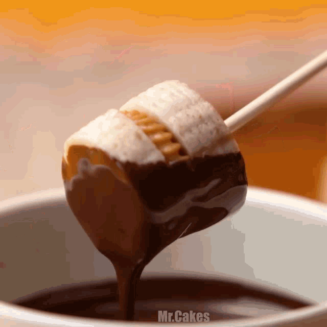 a marshmallow is being dipped into a chocolate fondue