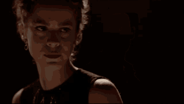 a man in a white shirt looks at the camera in the dark
