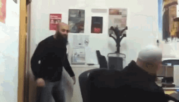 a man with a beard is dancing in a room with posters on the wall including one that says ' a '