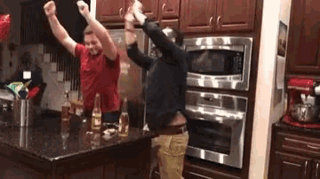 two men are dancing in a kitchen in front of a microwave .
