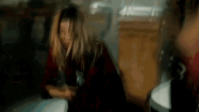 a woman in a red plaid shirt is holding a knife in her hand .