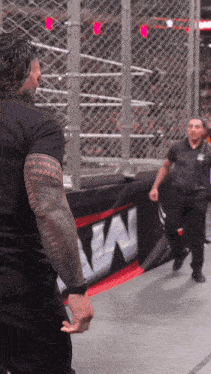 a man with a tattoo on his arm is standing in front of a sign that says w