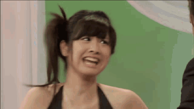 a woman in a black tank top is making a face