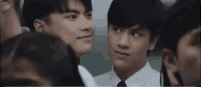a group of young men are standing next to each other in a crowd and looking at each other .