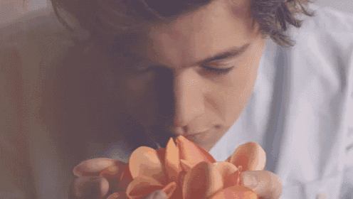a close up of a man smelling a flower petal
