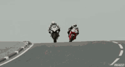 two motorcycle racers are racing on a road and one has the number 28 on his helmet .
