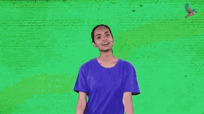 a woman is giving a thumbs up sign in front of a green wall that says well played