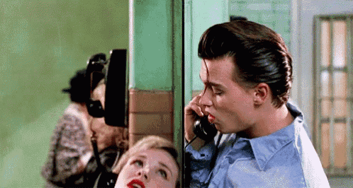a man is kissing a woman on the cheek while talking on a telephone .