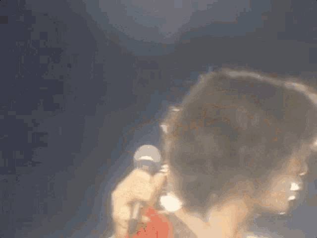 a woman is singing into a microphone with her hair blowing in the wind
