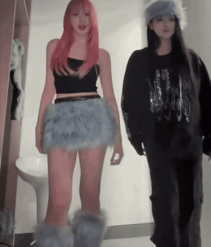 a girl with pink hair is wearing a black tank top and a blue skirt