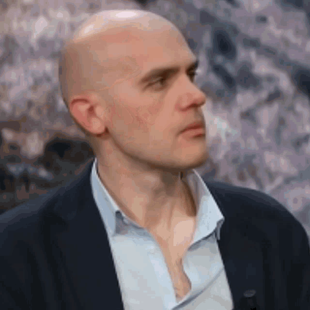 a bald man is wearing a suit and a light blue shirt