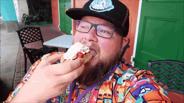 a man wearing glasses and a hat with a clock on it is eating a sandwich