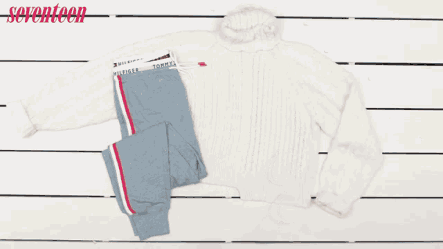 a person holding a pair of sneakers next to a sweater and pants