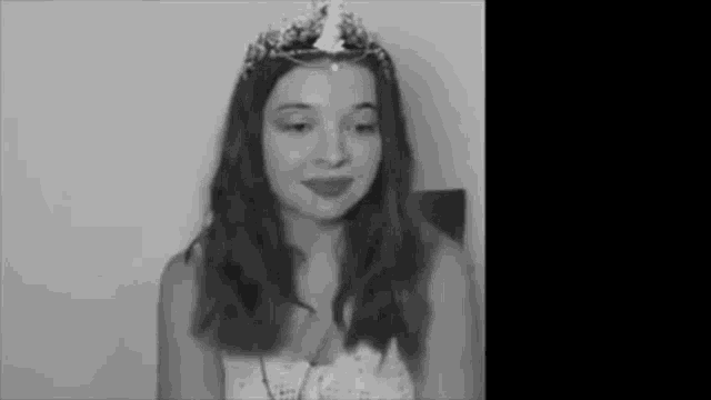 a black and white photo of a young girl wearing a tiara .