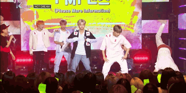 a group of young men are performing in front of a crowd and a sign that says " please more information "