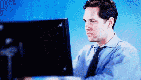 a man in a blue shirt and tie is looking at a computer monitor