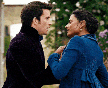 a man and a woman are standing next to each other and the woman is wearing a blue dress
