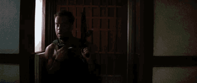 a man holding a gun in a doorway with a red door